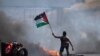 Un manifestante ondea la bandera palestina durante los enfrentamientos con las fuerzas israelíes en el puesto de control de Hawara, al sur de la ciudad cisjordana de Naplusa, el viernes 14 de mayo de 2021.