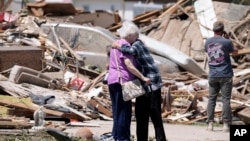 Joan Mitchell (izquierda) recibe el abrazo de su vecina Edith Schaecher frente a sus casas, destrozadas por un tornado, el 23 de mayo de 2024, en Greenfield, Iowa. 