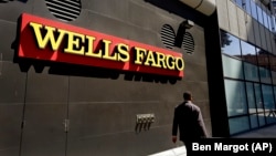 FILE - A man passes by a Wells Fargo bank office in Oakland, Calif., July 14, 2014.