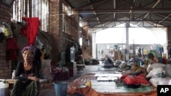 An elderly Kachin refugee and children, inside a shelter, look after the belongings of others who were out working near the China-Burma border in Yunnan province, China, August 11, 2012.