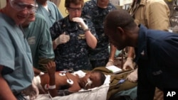 Medical professionals aboard the Military Sealift Command hospital ship USNS Comfort (T-AH 20) treat a six-year-old Haitian boy in the casualty receiving room aboard the 1,000-bed hospital ship.