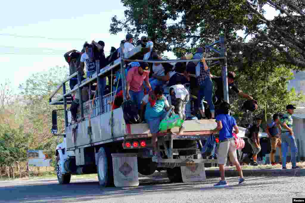 Un grupo de hondureños se suben a un camión para continuar su viaje hacia Estados Unidos.