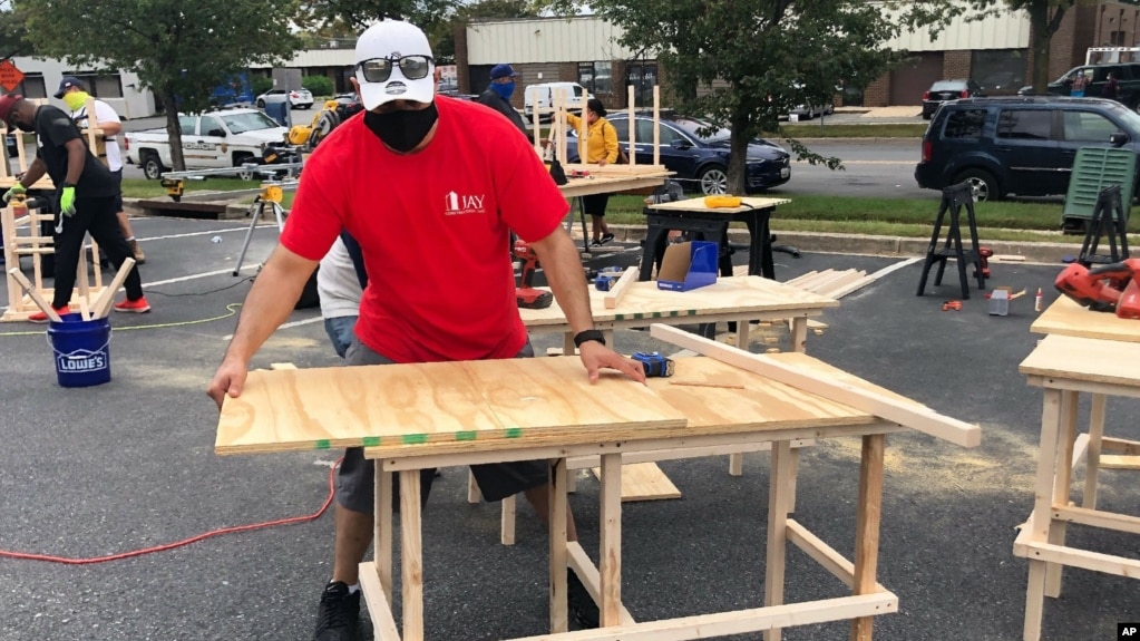 In this photo provided by Jessica Berrellez, her husband, Al Berrellez, builds a desk in Gaithersburg, Md., on Friday, Sept. 25, 2020. (Jessica Berrellez via AP)