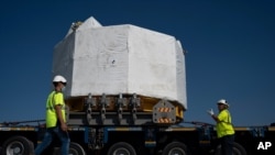 Workers secure a central solenoid magnet for the ITER project as it departs from Berre-l'Etang in southern France, Sept. 6, 2021.