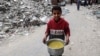 Gazzeli bir çocuk yardım kuruluşunun sağladığı bir tencere iftar yemeğiyle enkaz yığınları arasında yürürken