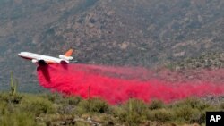 Heat ripples distort an air tanker as it drops retardant on the Bighorn Fire along the western side of the Santa Catalina Mountains, June 12, 2020, in Oro Valley, Ariz.