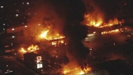 FILE - In this April 29, 1992 file photo, several buildings in a shopping center are in flames before firefighters can arrive as rioting erupted in South-Central Los Angeles following the acquittal of four police officers in the videotaped beating of Rodney King. (AP Photo/Reed Saxon, File)
