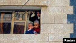 Anak-anak melongok ke luar jendela untuk melihat situasi ledakan di Sana'a, Yaman (22/1).