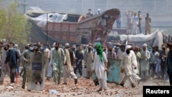 Supporters of the banned Islamist political party Tehreek-e-Labbaik Pakistan (TLP) with sticks and stones block a road during a protest in Lahore, Pakistan, Apr. 18, 2021. 