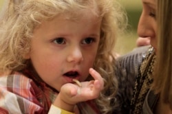 In this Nov. 11, 2011 photo, Corinne Hufft, right, of Dallas, feeds her daughter Ella Hufft, 3, a boiled mealworm as visitors sample Thanksgiving-inspired foods with insects at the Audubon Insectarium in New Orleans. (AP Photo/Gerald Herbert)