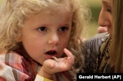 In this Nov. 11, 2011 photo, Corinne Hufft, right, of Dallas, feeds her daughter Ella Hufft, 3, a boiled mealworm as visitors sample Thanksgiving-inspired foods with insects at the Audubon Insectarium in New Orleans. (AP Photo/Gerald Herbert)