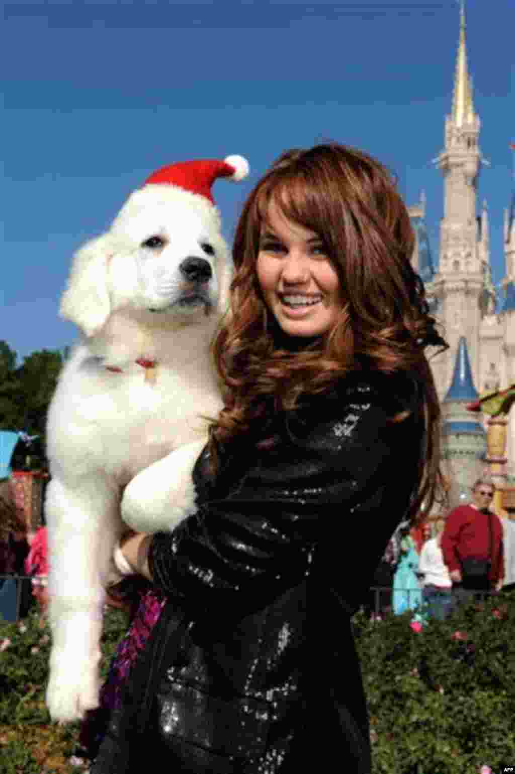 In this publicity image released by Disney, actress and singer Debby Ryan, star of Disney Channel's "The Suite Life on Deck," with the canine star of the new Disney holiday movie "The Search for Santa Paws" on Thursday, Dec. 2, 2010 while taping a segmen