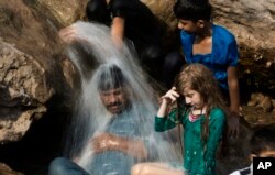 FILE - A family cools off in a stream during a heat wave, in Islamabad, Pakistan, May 30, 2017. The town of Turbat in southwestern Pakistan reported a temperature of 54 degrees Celsius in May.