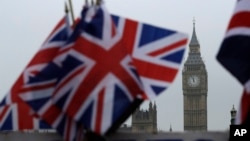 FILE - Union flags are displayed on a tourist stall, backdropped by the Houses of Parliament and Elizabeth Tower containing the bell known as Big Ben, in London, Feb. 8, 2017. 