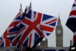 Union flags displayed on a tourist stall, backdropped by the Houses of Parliament and Elizabeth Tower containing the bell know as Big Ben, in London, Feb. 8, 2017.