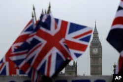 FILE - Union flags displayed on a tourist stall, backdropped by the Houses of Parliament and Elizabeth Tower containing the bell know as Big Ben, in London, Feb. 8, 2017.