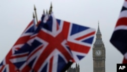 Union flags displayed on a tourist stall, backdropped by the Houses of Parliament and Elizabeth Tower containing the bell know as Big Ben, in London, Wednesday, Feb. 8, 2017.