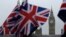 FILE - Union flags are displayed on a tourist stall, backdropped by the Houses of Parliament and Elizabeth Tower containing the bell known as Big Ben, in London, Feb. 8, 2017. 