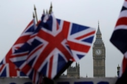 FILE - Union flags displayed on a tourist stall, backdropped by the Houses of Parliament and Elizabeth Tower containing the bell know as Big Ben, in London, Feb. 8, 2017.