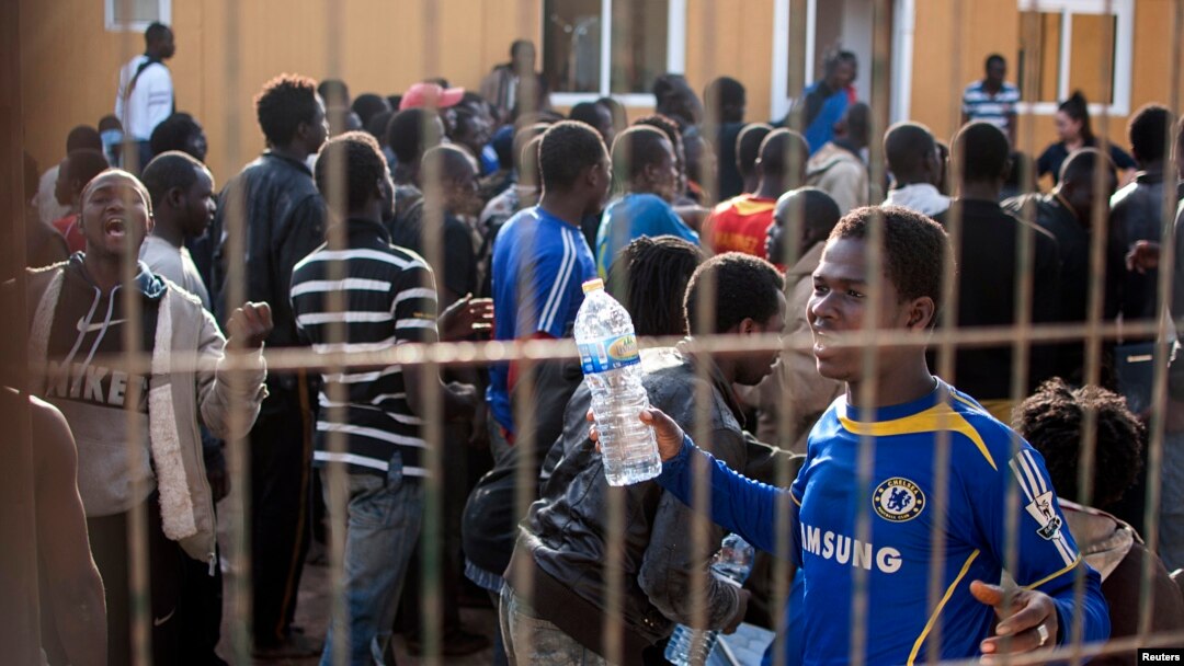 Would-be immigrants react from behind the fence of a temporary immigrant holding center after crossing the border from Morocco to Spain's north African enclave of Melilla March 18, 2014.