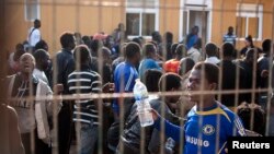 Would-be immigrants react from behind the fence of a temporary immigrant holding center after crossing the border from Morocco to Spain's north African enclave of Melilla, March 18, 2014.