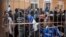 Would-be immigrants react from behind the fence of a temporary immigrant holding center after crossing the border from Morocco to Spain's north African enclave of Melilla, March 18, 2014.