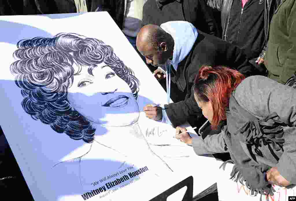 Fans sign a poster of Whitney Houston near a funeral service for the singer at the New Hope Baptist Church in Newark, New Jersey, February 18, 2012. (AP)