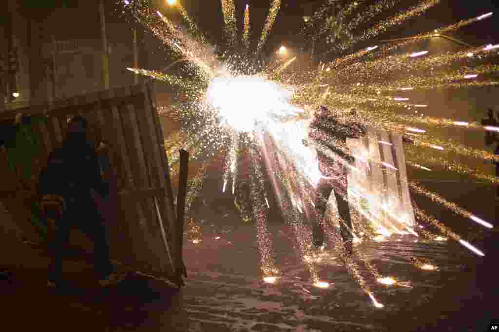 A burst of fireworks go off near members of the so-called Black Bloc anarchist group during clashes with police after a march of striking teachers took place to mark National Teachers Day, in Rio de Janeiro, Brazil, Oct. 15, 2013. 
