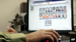 FILE - A law enforcement officer looks through photos in a facial-recognition system. Some critics consider use of the technology as discriminatory and lacking in proper oversight.