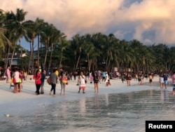 FILE - Tourists visit a beach during sunset in Boracay, Philippines, Oct. 26, 2018.