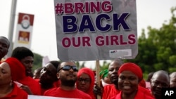 FILE - Nigerians carry a sign calling on the government to rescue the kidnapped girls during a demontration in Abuja.