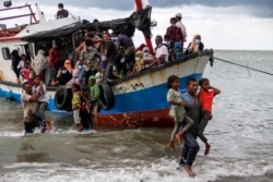 Warga setempat mengevakuasi pengungsi Rohingya dari sebuah kapal di pantai Aceh Utara, 25 Juni 2020. (Antara Foto / Rahmad / via REUTERS)