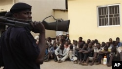 Policeman stand guard as suspected rioters await a court hearing in Kaduna, Nigeria, April 20, 2011