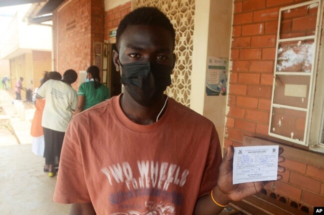 A Ugandan man holds a vaccination card that proves he has received the yellow fever vaccine, at Kiswa Health Center III in Kampala, Uganda Tuesday, April 2, 2024. (AP Photo)