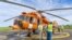 Humanitarian workers discuss near a United Nations Humanitarian Air Service (UNHAS) helicopter painted in orange color as part of efforts to improve safety of operations in the restive eastern Democratic Republic of Congo in this photograph released on April 20, 2023.