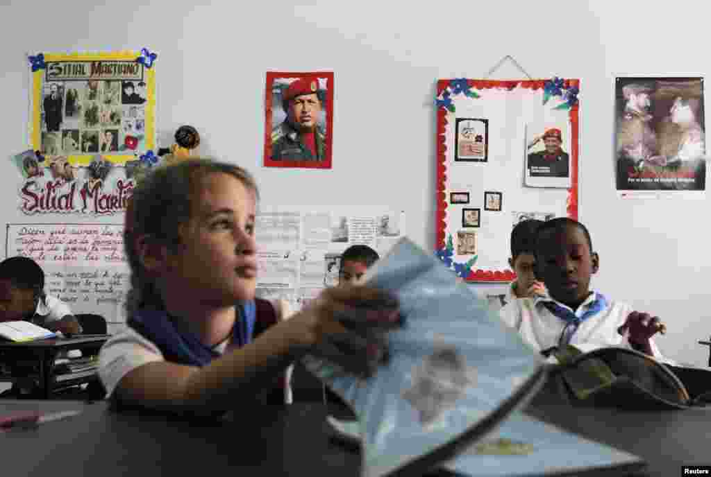 Schoolchildren attend a class while sitting near photographs of Venezuela&#39;s late President Hugo Chavez and Cuba&#39;s former President Fidel Castro at the Hugo Chavez Frias primary school in Havana. Different activities will be held in Cuba and in other countries during February and early March as a tribute to Chavez who died March 5, 2013.