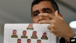 El ministro de Relaciones Interiores y Justicia de Venezuela, Miguel Rodríguez Torres, muestra fotos de los presuntos complotados.