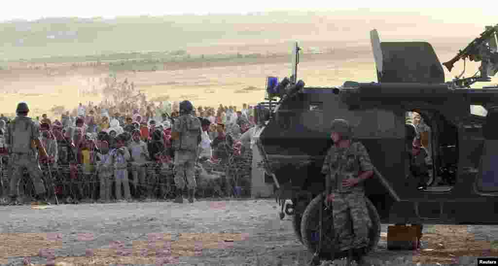 Turkish Deputy Prime Minister Numan Kurtulmus told CNN Turk television on Saturday that 45,000 Syrian Kurds had crossed the border since Turkish authorities opened it on Friday. Earlier this week, Turkish soldiers stand guard as Syrians wait behind the bo