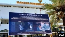 Salah satu poster aksi menolak tambang emas Tumpang Pitu di depan Kantor Gubernur Jawa Timur, Surabaya (VOA/Petrus Riski).