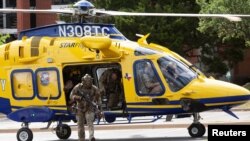 Law enforcement personnel exit a helicopter after it dropped them off next to the Arboretum Oaks apartment complex, the scene of a deadly shooting in Austin, Texas, April 18, 2021.