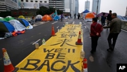 Spanduk tuning bertuliskan "We'll be back" dipamerkan oleh para pemrotes di luar kantor pusat pemerintah Hong Kong, Rabu (10/12).