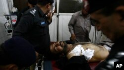 Pakistani police officers surround their injured colleague at a local hospital in Peshawar, Pakistan, April 10, 2013.