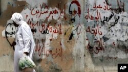 FILE - A man walks past graffiti on a wall portraying opposition activist Ibrahim Sharif, in the western village of Malkiya, Bahrain.