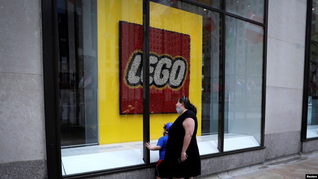 Una mujer y un niño observan la vitrina de la tiena Lego ubicada en el Centro Rockefeller en la 5ta Avenida, en Nueva York, que ha permanecido cerrada por la pandemia del coronavirus.