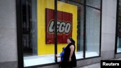 Una mujer y un niño observan la vitrina de la tiena Lego ubicada en el Centro Rockefeller en la 5ta Avenida, en Nueva York, que ha permanecido cerrada por la pandemia del coronavirus.