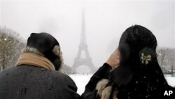 People take snapshots near the Eiffel Tower after snow fell on the French capital, 8 Dec. 2010