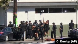 Police officers use a mirror to see inside a Trader Joe's store in the Silver Lake neighborhood of Los Angeles, July 21, 2018.