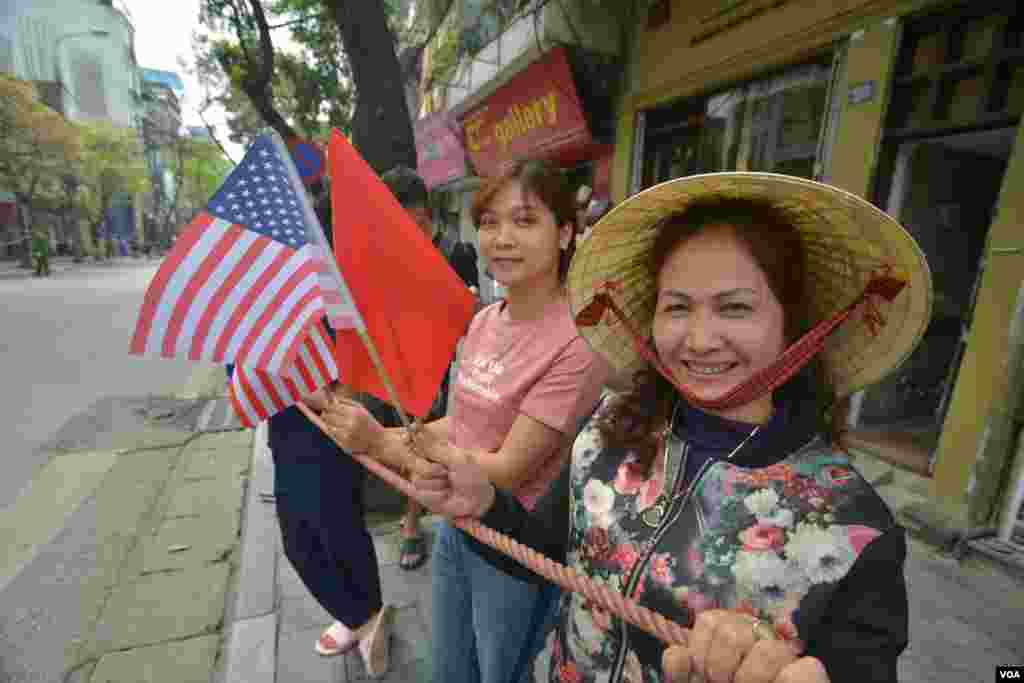 트럼프 대통령의 차량 행렬을 보기 위해 거리로 나온 하노이 시민들이 미국 성조기와 베트남 금성홍기를 들고 있다.