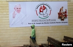 FILE - A boy is pictured below a banner of Pope Francis before a special mass at St. Joseph the Worker Catholic Parish where Pope Francis is expected to visit Kangemi, a slum that is home to 650,000 people in Kenya's capital Nairobi, Nov. 22, 2015.