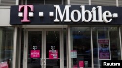 FILE - A sign for a T-Mobile store is seen in Manhattan, New York, April 30, 2018. 